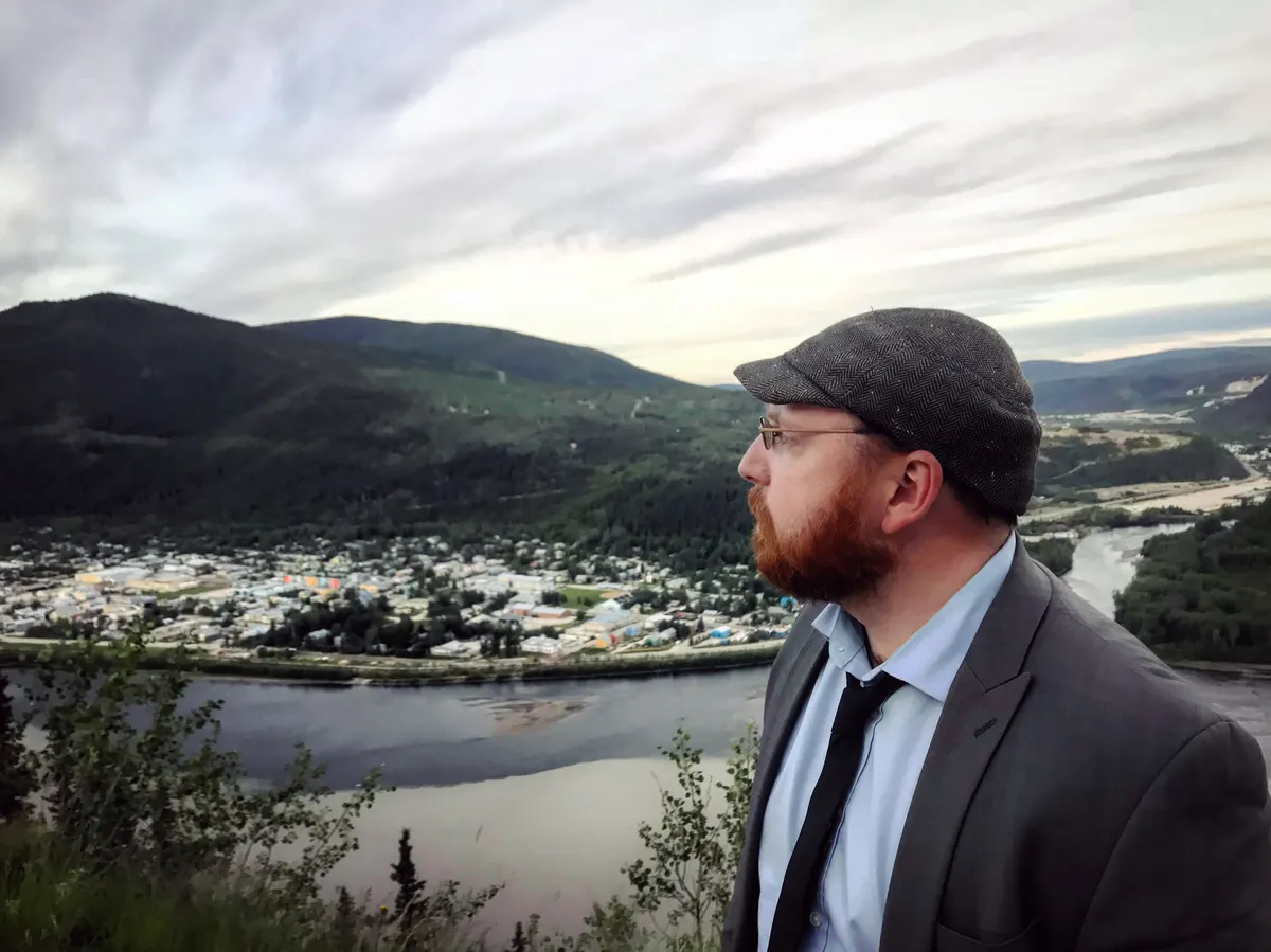 Man standing in profile looking over river